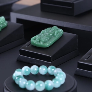 Green jade pendant and beaded bracelet displayed on a professional black leather jewelry tray