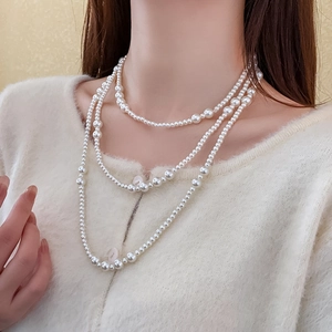 Detail of layered white pearl necklace worn over a cozy cream sweater for elegant styling