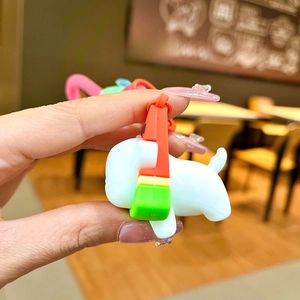 Side view of white cartoon puppy keychain with colorful silicone strap detail