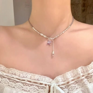 Dettaglio dell'elegante collana di perline con farfalla in zircone viola su modella