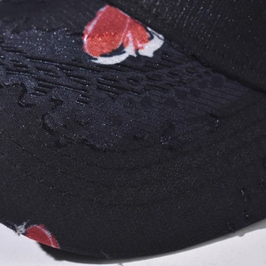 Close-up of black mesh fabric on a baseball cap with red and white embroidered heart pattern