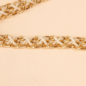 Detail of golden metal chain interwoven with white pearls for an elegant waist belt