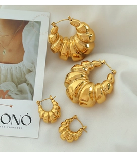 Detail showing two sizes of gold croissant earrings with textured geometric design