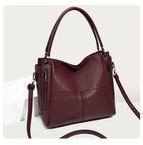 Detail of burgundy leather tote bag with lychee texture and side zippers