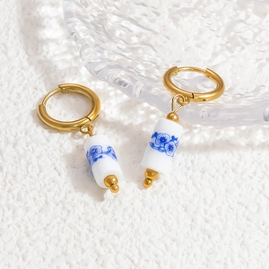 Macro shot of 18k gold hoop earrings with blue and white porcelain ceramic pendants