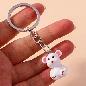 Detail view of a cute white bear keychain with a silver metal ring held by a person