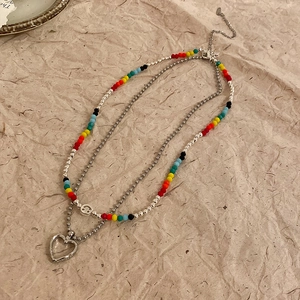 Detail of double-layer beaded necklace with colorful beads and silver heart pendant