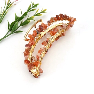 Macro detail of handmade banana hair claw with red and orange natural crushed stones
