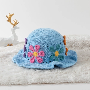 Handmade sky blue crochet bucket hat with colorful floral patterns on white faux fur
