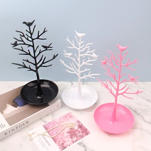 Three bird tree jewelry organizers in black, white, and pink with a round base tray