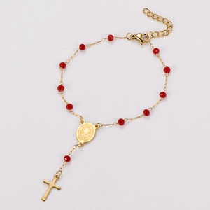 Détail d'un bracelet chapelet religieux avec perles rouges facettées et pendentif croix dorée