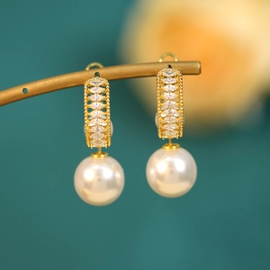 Detailed close-up of pearl drop earrings with marquise-cut crystals on a gold frame