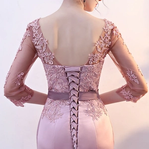 Close-up of elegant V-back lace embroidery and lace-up corset on a mauve evening dress