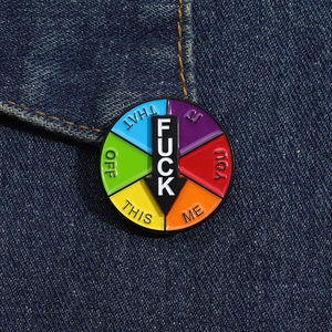 Macro shot of spinning enamel brooch with colorful mood wheel on blue denim fabric