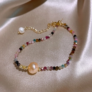 Macro view of freshwater pearl bracelet with colorful gemstones and golden fringe detail
