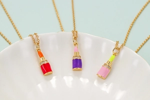 Macro view of gold-plated lipstick pendants with colorful enamel and sparkling rhinestones