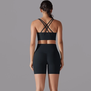 Vista posteriore del set da yoga nero con reggiseno sportivo incrociato e pantaloncini a vita alta