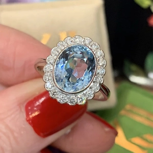 Elegant floral silver ring with an oval light blue gemstone and CZ halo setting