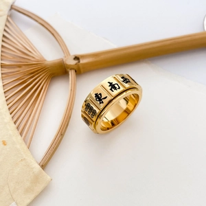 Macro shot of rotatable gold stainless steel ring with engraved mahjong tile symbols