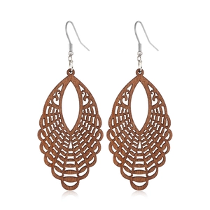 Macro view of brown teardrop wood earrings with intricate geometric cutout patterns