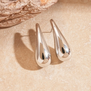 Polished silver teardrop earrings with a minimalist sleek design on a stone surface