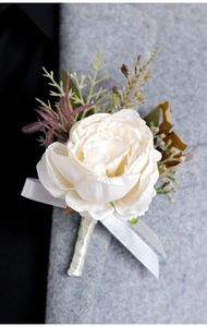 Close-up of cream satin rose boutonniere with green leaves on grey suit lapel