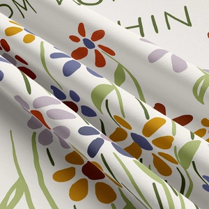 Detail of fabric texture showing colorful floral patterns and green letter prints on wall tapestry