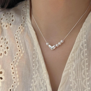 Close-up of minimalist 925 silver heart necklace with white pearls on a lace background