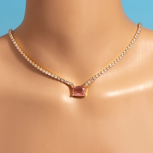 Detailed view of a gold tennis necklace with a radiant pink rectangular gemstone pendant
