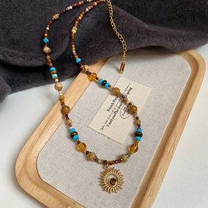 Detail of beaded sunflower necklace with natural stones and golden lobster clasp
