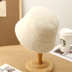 Close-up of soft beige teddy fleece bucket hat texture on a wooden stand