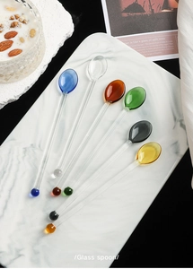 Detailed overhead view of six colorful glass stirring spoons for coffee and juice drinks