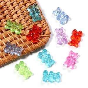 Macro detail of colorful translucent resin gummy bear charms on a woven mat for DIY crafts