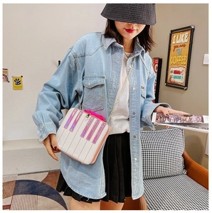 Sweet piano bow bag in white and pink with golden chain strap shown in a cafe setting