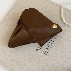 Detail of dark brown fabric hair clip with a vintage gold button on linen background