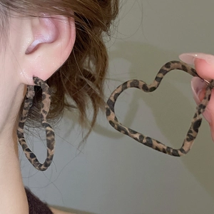 Gros plan de grandes boucles d'oreilles cœur léopard avec texture ondulée sur modèle