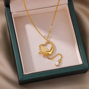 Detailed view of hollow heart and frosted butterfly pendant on gold plated necklace