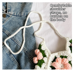 Detail of hand-knitted crochet puff flower bag with thick woven shoulder strap on denim