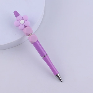 Detail of purple beadable pen with silicone flower and glitter body on white stand