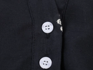 Close-up of black cotton-linen fabric texture with white buttons and stitching detail