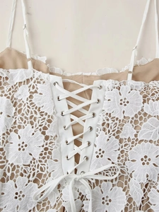 Détail du caraco en dentelle florale blanche avec œillets argentés et laçage croisé au dos