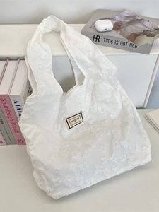 White jacquard tote bag with 3D floral texture and Pleasant Time label on desk