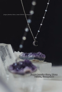 Detailed view of silver moon pendant with blue crystal beads on a thin titanium chain
