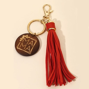 Detailed close-up of a MAMA engraved wood charm and vibrant red leather tassel keychain