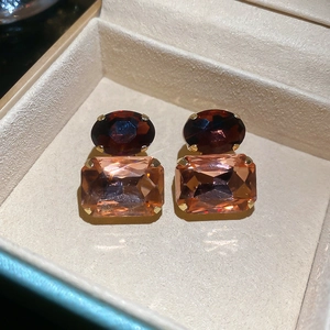 Close-up of vintage earrings with oval brown and rectangular pink gemstones in gold claws