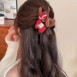 Detail of reindeer plush hair claw clip and Christmas stocking charm on long wavy hair