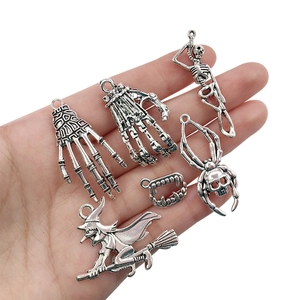 Detailed view of silver Halloween metal charms including skull hand and witch designs