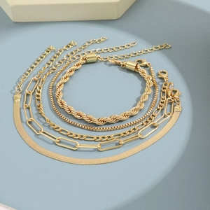 Detailed set of five gold-toned bohemian chain bracelets on a light blue display tray