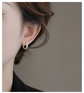 Close-up of polished S925 sterling silver daisy flower hoop earring worn by a model