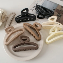 Flat lay of matte cream and earthy tone large hair claw clips on a white plate